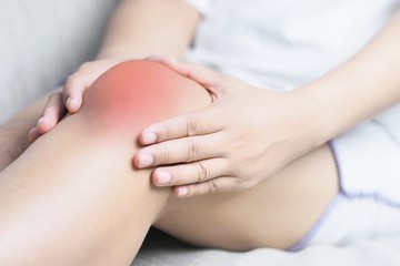 Fototapeta na wymiar Bone pain or knees around the knee , The girl's hand is holding the knee area.