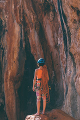 Climber in a helmet looks at a rock wall.