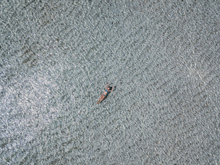 Young woman swimming in transparent sea water, drone aerial view. Gili islands, Indonesia