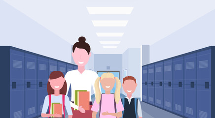 female teacher with schoolchildren group standing in school corridor interior with rows of blue lockers education concept horizontal portrait flat