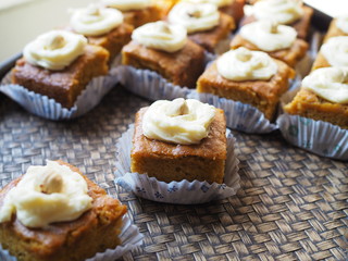 Slice of carrot cake with cream cheese frosting on wooden tray