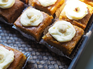 Slice of carrot cake with cream cheese frosting on wooden tray