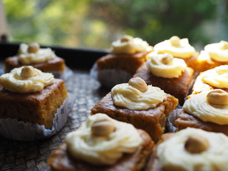 Slice of carrot cake with cream cheese frosting on wooden tray