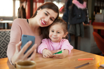 Happy mother make selfie with her smartphone in cafe