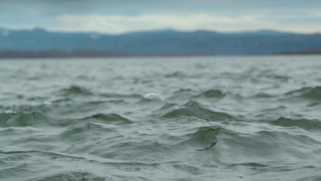 SLOW MOTION 4K Looking out over choppy water towards mountain in the background
