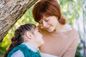 Mother and daughter having fun near blossom apple trees