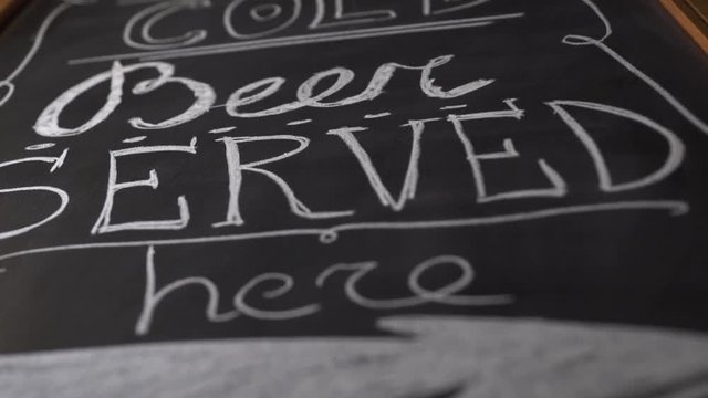 Black chalkboard with invite to beer pub close up. Beer menu driwing on chalk board in brewery bar. Inscription with white chalk in brewery for client.