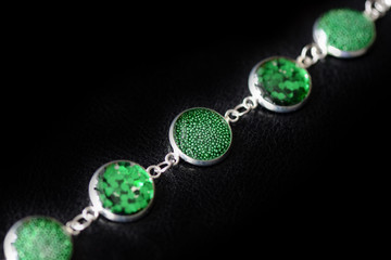 Resin bracelet with green sparkles on a dark background close up