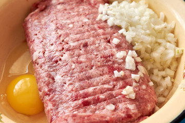 fresh beef and pork minced meat sprinkled with white onions and chicken egg for making cutlets and schnitzel in a yellow iron plate