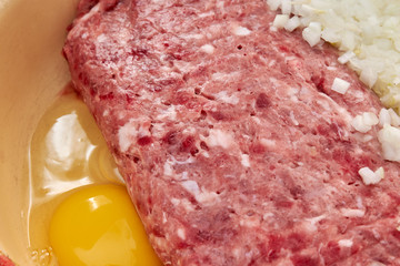fresh beef and pork minced meat sprinkled with white onions and chicken egg for making cutlets and schnitzel in a yellow iron plate. fresh meat