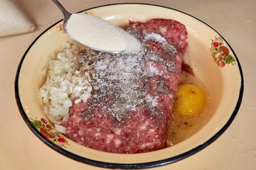 fresh beef and pork minced meat sprinkled with white onions and chicken egg and salt and pepper Sprinkle sugar with a spoon. for making cutlets and schnitzel in a yellow iron plate. meat patties