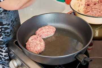 female chef at home in the kitchen frying on a hot pan on an electric stove meatballs pork and beef
