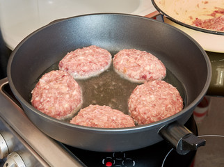 At home, in the kitchen, roasting in a hot pan on an electric stove meatball patties made from pork and beef. cooking at home. tasty healthy food