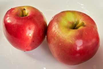 two red apples lie on a white plate. fruits and vegetables.