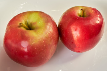 two red apples lie on a white plate. fruits and vegetables. vitamin c