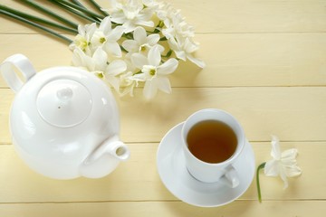 Spring tea.Flat lay.notebook, white teapot, a cup of tea, a bouquet of white daffodils on a  yellow background.top view, copy space.Spring mood