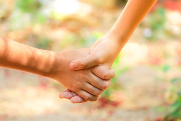 the hands of a man holding a girl's hand on a blurred background.