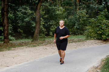 Fototapeta premium very fat guy runs in the park in summer