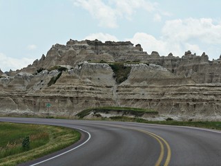 A paved road winds alongside incredible land and rock formations at the Badlands National Park in South Dakota.