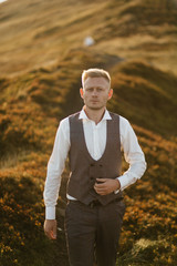 Obraz premium young man standing on a mountain at sunset