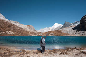 Fototapeta na wymiar Tourist raise hand up with turquoise lake and mountain range on peak