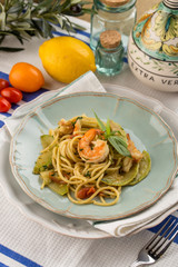 Spaghetti with shrimps tomato and zucchini on textile napkin