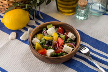Fresh Greek salad in bowl with olives tomato feta cheese cucumber and onion on textile napkin