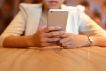 image selective focus on wooden table work of office with business woman using mobile phone technology
