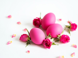 Pink Easter eggs on light background with  pink roses. Holiday card, copy space.