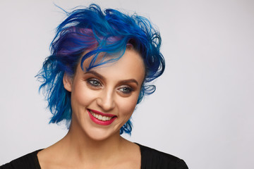 Portrait of a laughing woman with blue and pink hair in black dress. Studio photo session