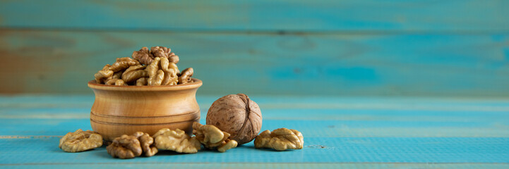 Walnuts on blue rustic table in wooden bowl