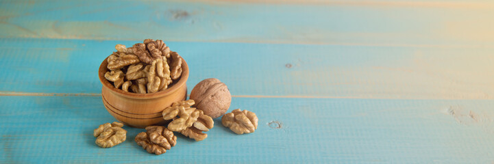 Walnuts on blue rustic table in wooden bowl