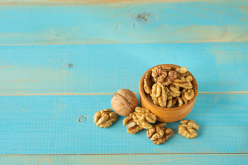 Walnuts on blue rustic table in wooden bowl