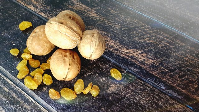 Three walnuts and a white isam lie on a wooden table. Still life.