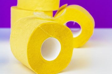 Minimalistic composition of bright yellow toilet paper rolls on purple background