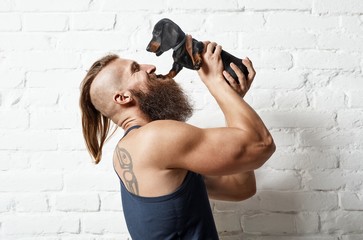 Young bearded man lifting little puppy