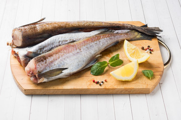 Raw fresh Pollock fish on a wooden Board with lemon