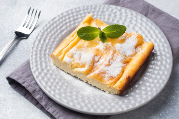 Cottage cheese casserole on a plate with powdered sugar and mint leaves. Selective focus