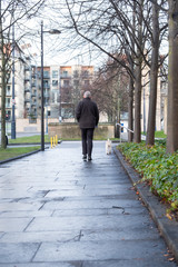Fototapeta na wymiar Elderly gray-haired old man walks the dog on a Scottish street