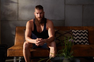 Young bearded man sitting in dark room at home