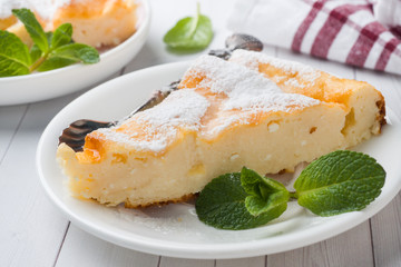 Cottage cheese casserole on a plate with powdered sugar and mint leaves. Selective focus