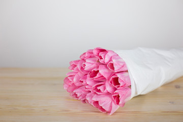 Gently pink tulips in white wrapping paper close-up. Flower background