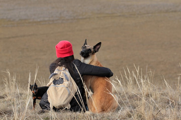 The girl and dogs in the spring nature, the Belgian Shepherd Malinois breed and miniature pinscher
