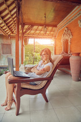 Obraz premium Girl using laptop on a home porch / terrace.