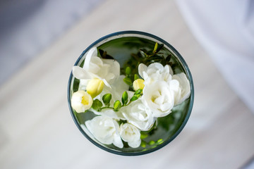 white freesia flowers in a glass, top view, different focus