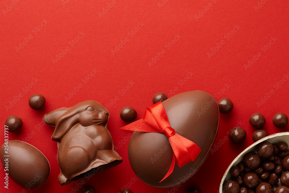 Wall mural easter composition with chocolate eggs and bunny on red background, holiday concept