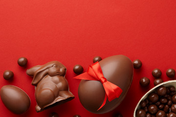 Easter composition with chocolate eggs and bunny on red background, holiday concept