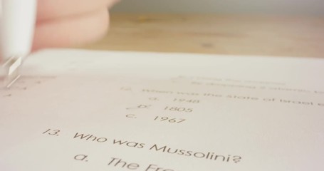 Tracking macro shot of pen marking answers in a history test in school