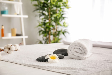 Fototapeta na wymiar Massage stones and towels on table in spa salon