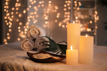 Plate with sea salt and burning candles on table in spa salon